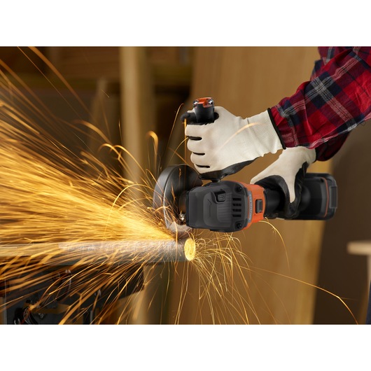 Photo of BLACKDECKER BCG6L8N cordless angle grinder cutting metal pipe with sparks flying, operator wearing gloves