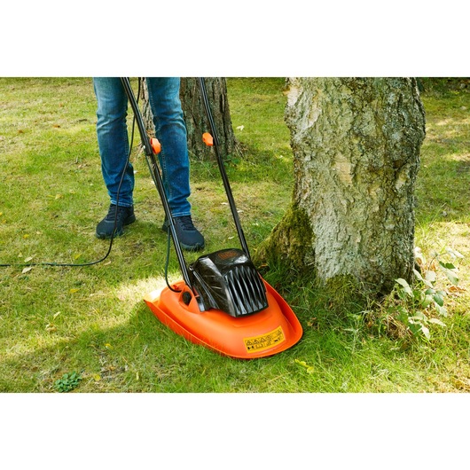 BLACK+DECKER BEMWH551 orange and black electric hover mower cutting grass around a tree.