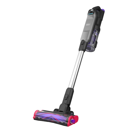 A BLACK+DECKER cordless stick vacuum cleaner with a grey and black body, a transparent dustbin, and a pink and purple brush head, photographed against a white background.