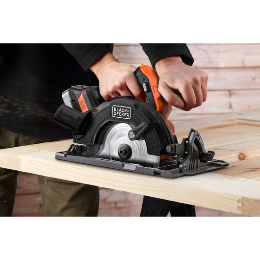 Photo of BLACKDECKER BLCCS78E1 cordless circular saw cutting wood, close-up of blade and handle.