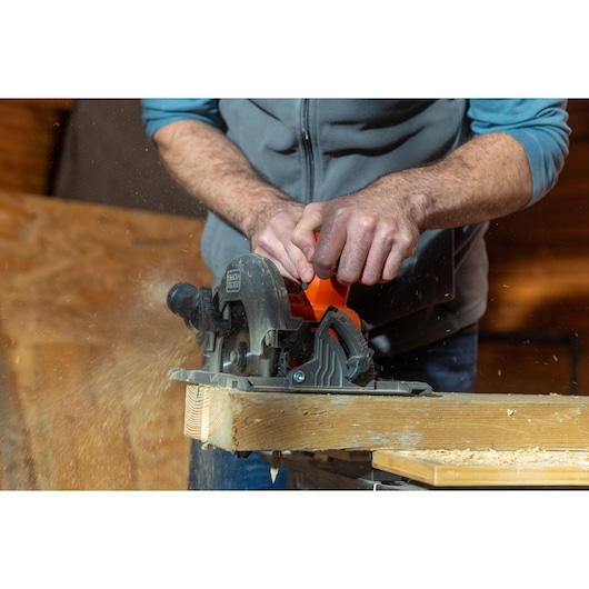 BLACK+DECKER BLCCS78M1 circular saw cutting wood, sawdust flying, close-up of user's hands during operation.