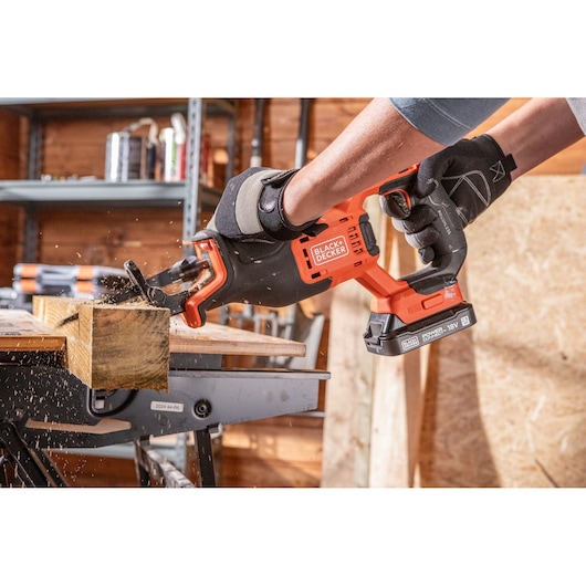 BLACK+DECKER BLCR78E1 cordless reciprocating saw cutting wood, shown in use in workshop.