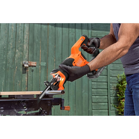 BLACK+DECKER BLCR78E1 cordless reciprocating saw being used to cut metal pipe outdoors.