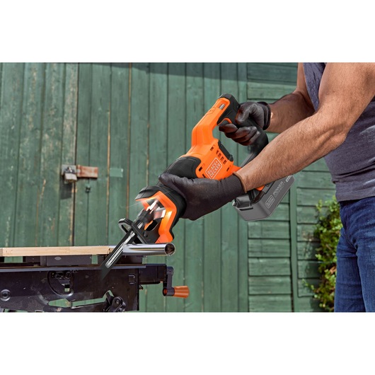 BLACKDECKER BLCR78M1 reciprocating saw with black and orange grip cutting metal pipe outdoors.