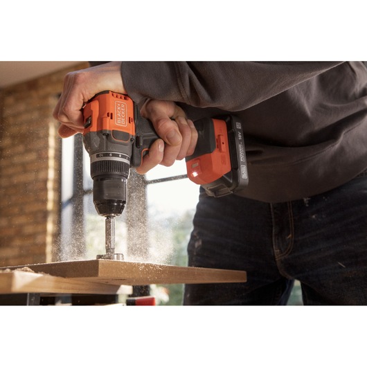 BLACKDECKER cordless drill BLD782E2K in use drilling wood, close-up with dust flying.