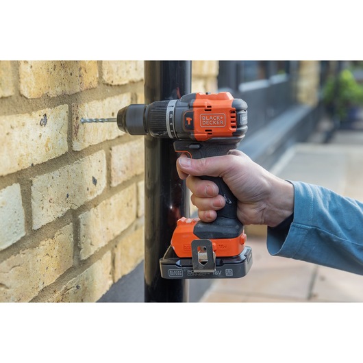 Photo of BLACKDECKER BLD783E1K cordless drill used on a brick wall, orange and black color, product in use.