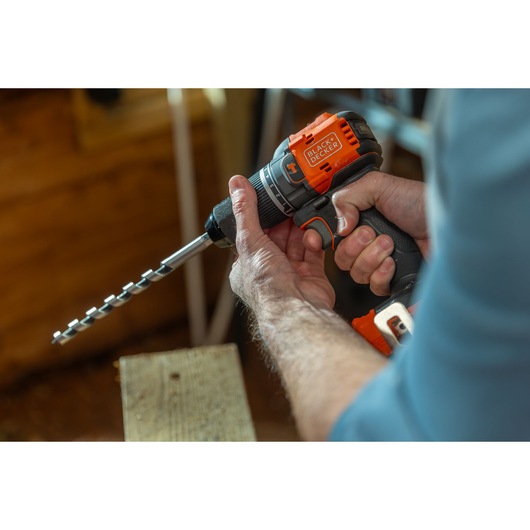 Photo of BLACK+DECKER cordless drill BLD783E1K with auger bit, held by a person while working on wood.