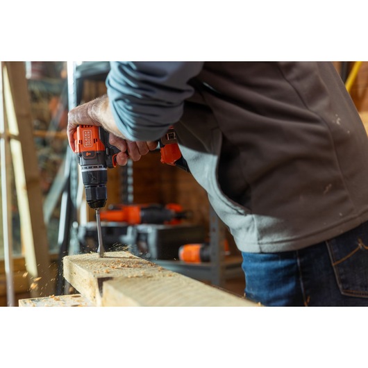 Photo of BLACK+DECKER BLD783N cordless drill in use, drilling into wood, person wearing gray jacket.