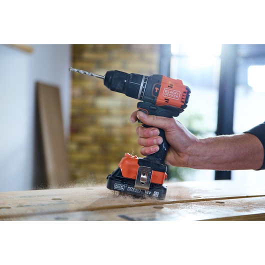 BLACK+DECKER BLD783N cordless drill in use, orange and black, drilling into wood, side angle.