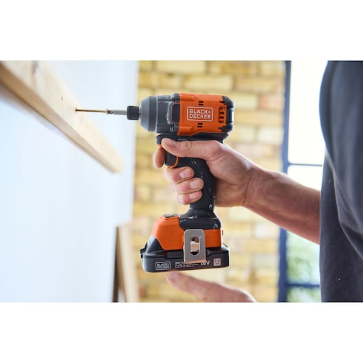 Photo of BLACK+DECKER BLIM78E1K cordless impact driver, black and orange, driving a screw into wood.