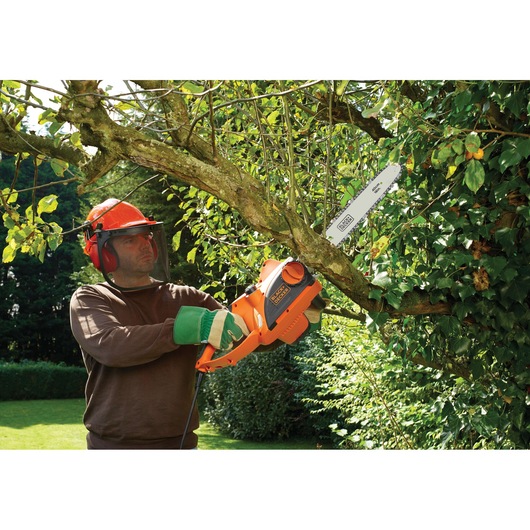 BLACKDECKER CS2040 chainsaw used outdoors for cutting tree branches, visible orange body and blade.