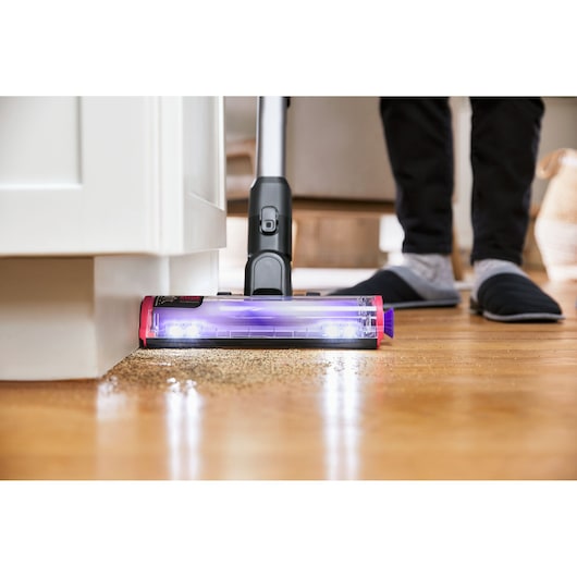 BLACK+DECKER SUMMITSERIES cordless stick vacuum vacuuming debris under cabinet using edge-to-edge technology