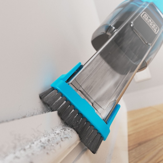 Close-up of the BLACK+DECKER Dustbuster vacuuming dust from a skirtingboard using the flip brush.