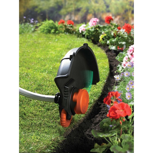 BLACKDECKER GL9035 grass trimmer edging a lawn beside colorful flowers in a garden, close-up outdoor view.