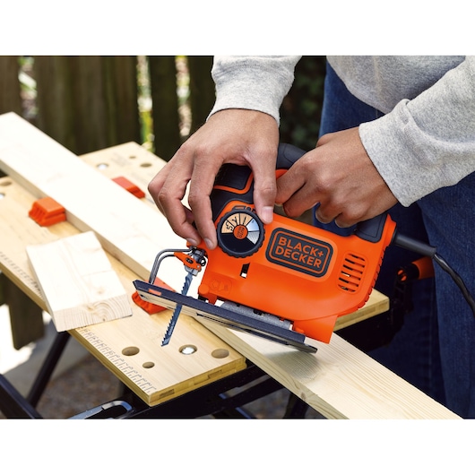 A man adjusts the AUTOSELECT® dial of the BLACK+DECKER® 550W AUTOSELECT® Pendulum Jigsaw.