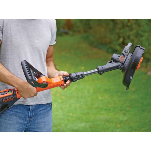 Photo of BLACKDECKER STC1840EPC grass trimmer in use outdoors, orange and black, ergonomic handle visible.